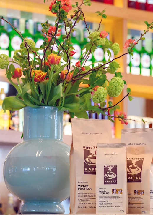 Eine Vase mit bunten Blumen und Kaffeebohnen auf einem Tisch im Das Einstein-Mommseneck.