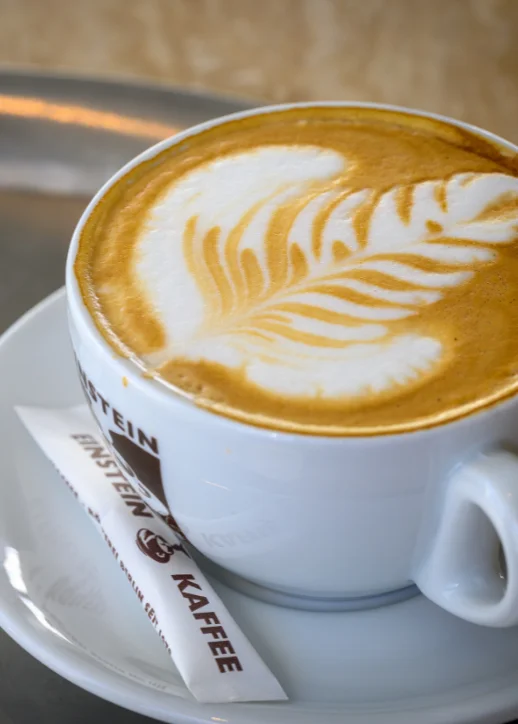 Eine Tasse Kaffee auf einem Tisch, dampfend und aromatisch, umgeben von einer gemütlichen Atmosphäre.