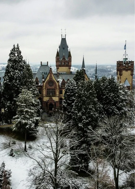 Schloss Drachenburg in Königswinter, umgeben von schneebedeckten Bäumen und einer winterlichen Landschaft