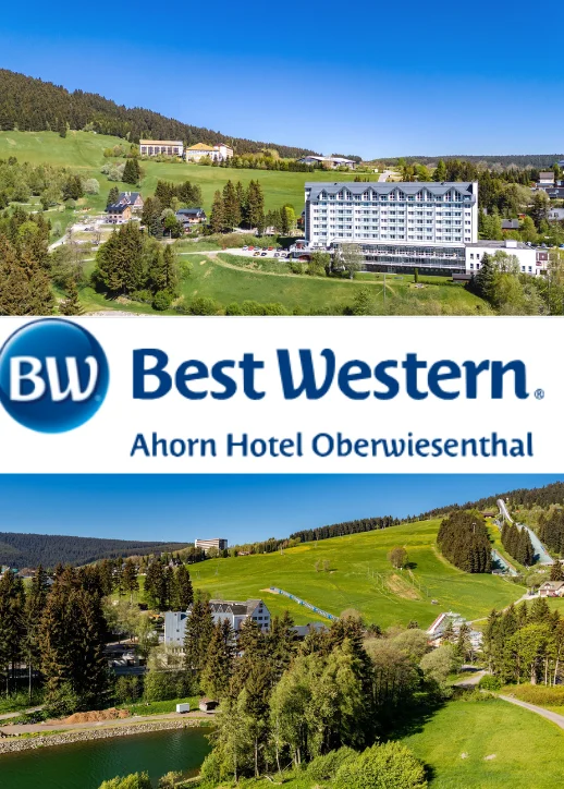 Hotelgebäude auf einer grünen Hügellandschaft mit Wald im Hintergrund und blauem Himmel