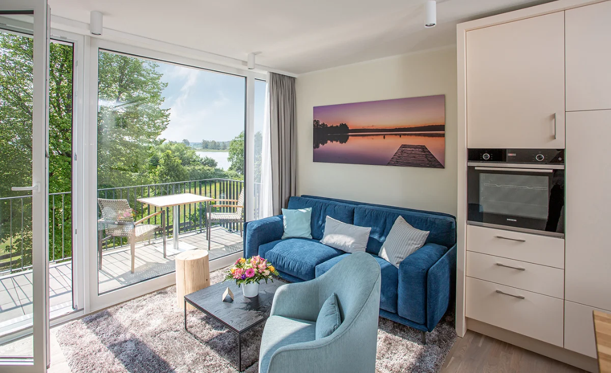 Gemütliches Wohnzimmer mit blauer Couch und Wasserblick im 5 Sterne Resort Müritz.