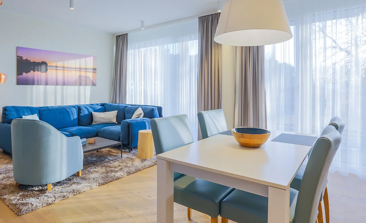 Elegantes Wohnzimmer im 5 Sterne Resort Müritz mit blauer Couch und Esstisch.