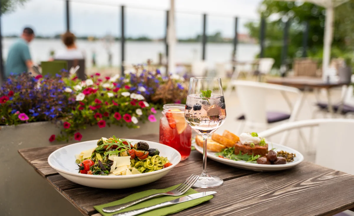 Ein Tisch mit zwei Tellern köstlichem Essen und einem Glas Wein im 5 Sterne Resort Müritz.