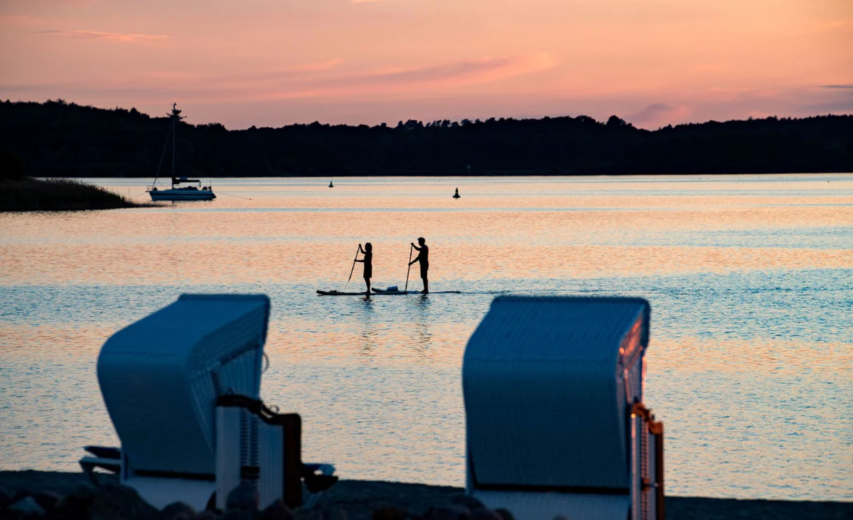 Ein Paar paddelt gemeinsam auf einem Paddleboard im 5 Sterne Resort Müritz.