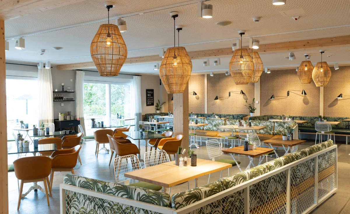 Ein Restaurant im 5 Sterne Resort Müritz mit vielen Tischen und Stühlen, ideal für gesellige Zusammenkünfte.