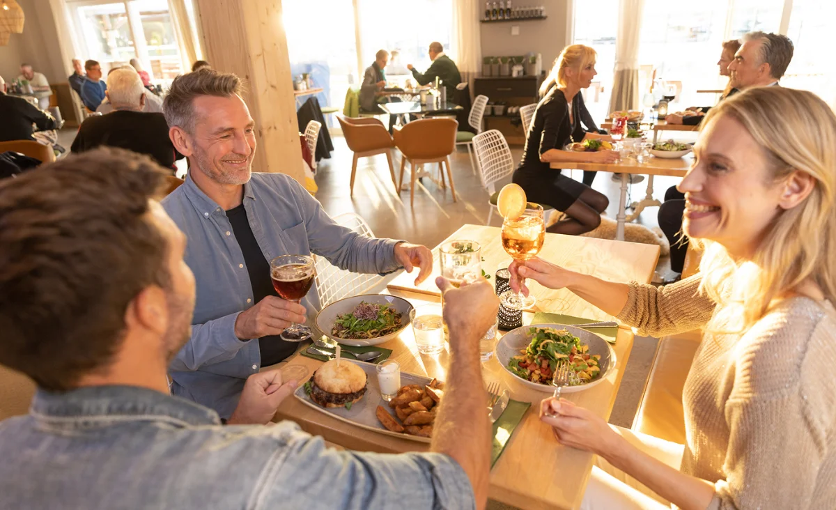 Eine Gruppe von Menschen stößt in einem Restaurant im 5 Sterne Resort Müritz an.