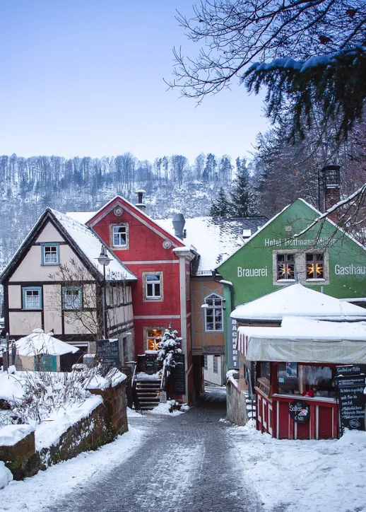 Winterlandschaft in Schmilka: Eine schneebedeckte Straße mit charmanten Häusern und schneebedeckten Bäumen.