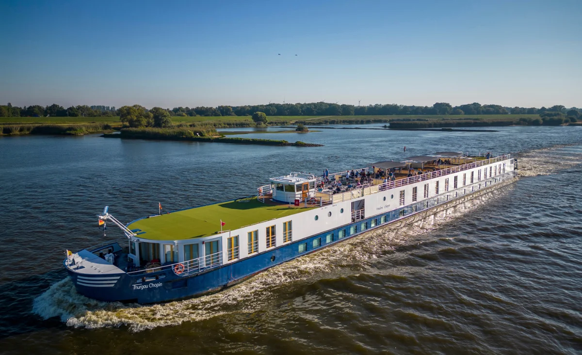 Ein großes blau-weißes Schiff gleitet den Fluss entlang auf der Kreuzfahrt von Prag nach Berlin.