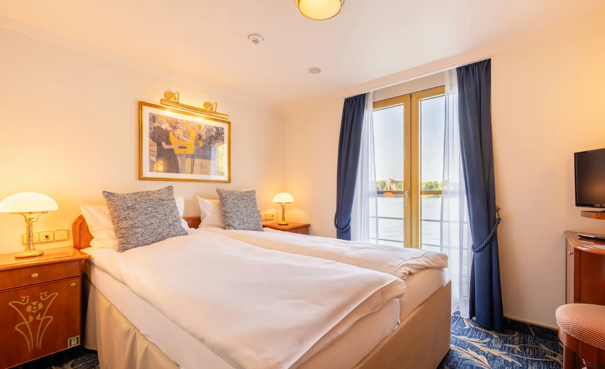 Ein Zimmer mit zwei Betten und einem Fernseher, ideal für die Kreuzfahrt von Prag nach Berlin.