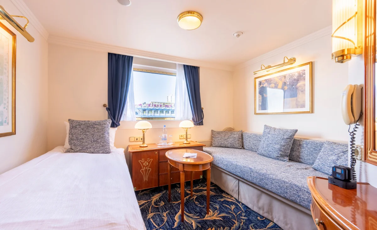Kleines Schlafzimmer mit einem Bett und einer Couch, ideal für eine entspannte Kreuzfahrt von Prag nach Berlin.