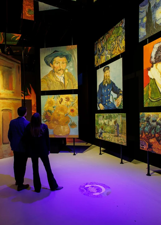 Ein Paar betrachtet Gemälde an einer Wand in einer Van Gogh immersiven Ausstellung.
