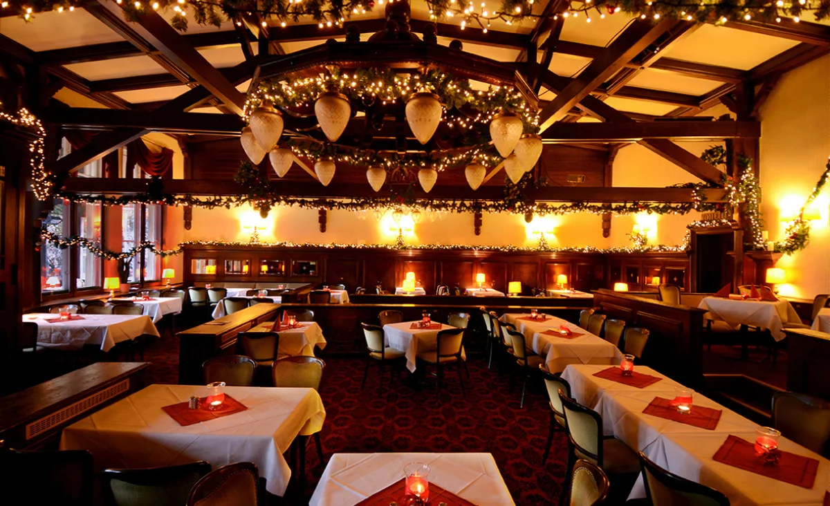 Restaurant Historisches Wirtshaus Moorlake mit festlich gedeckten Tischen und Stühlen für Weihnachten dekoriert.