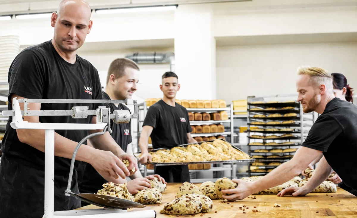 Eine Gruppe von Männern in der Stollenbäckerei Krause in Dresden, die gemeinsam Stollen backen.