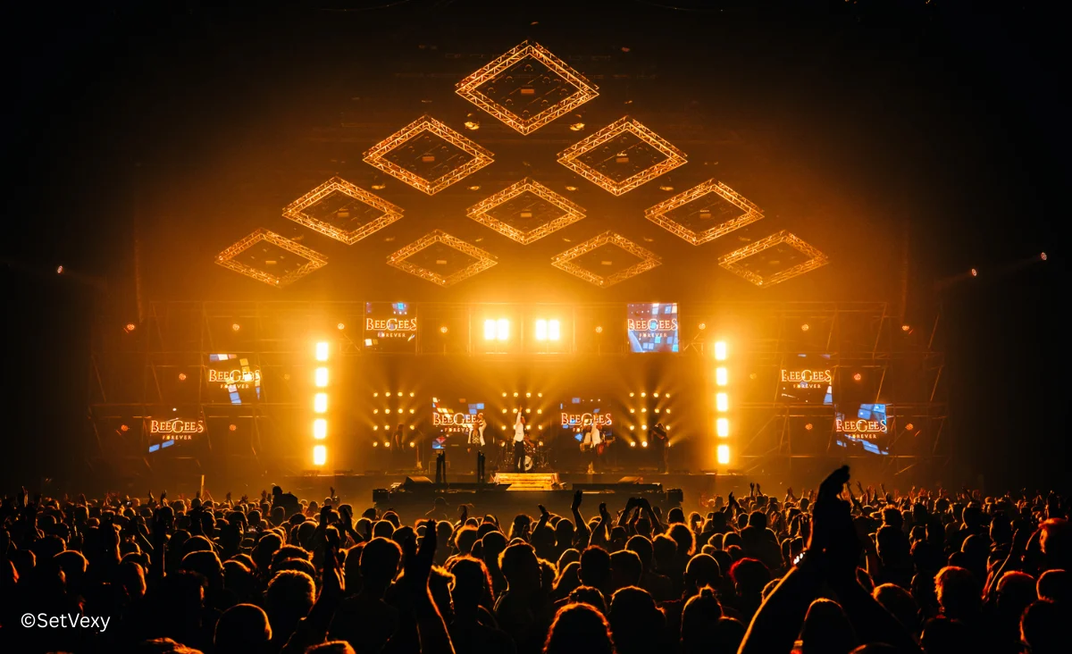 Bühne mit Lichtern und Menschen im Hintergrund während des Bee Gees Konzerts von Maincourse im Tempodrom Berlin.
