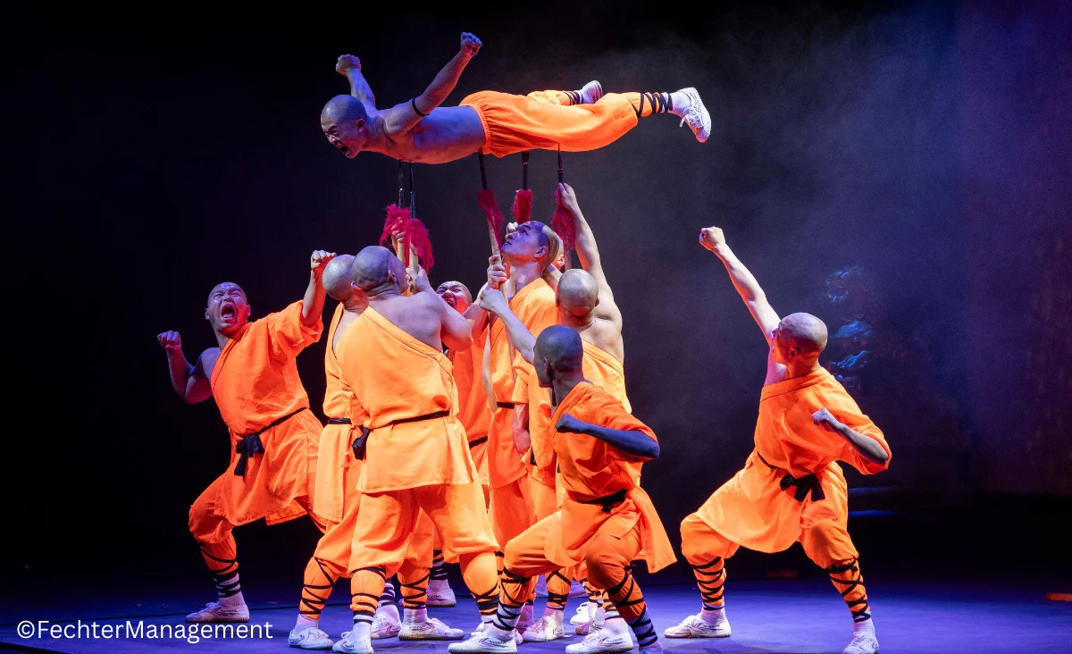Eine Gruppe von Männern in orangefarbenen Outfits führt einen Tanz auf.
