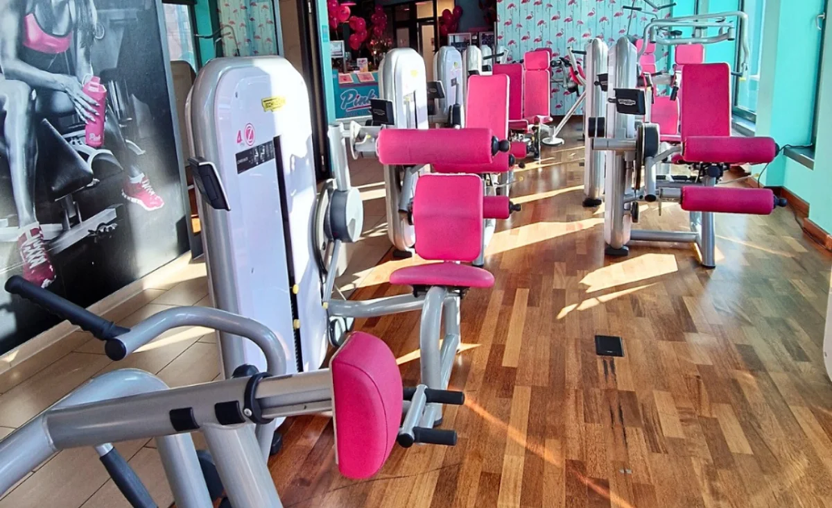 Ein modernes Gym, ausgestattet mit pinken und weißen Geräten, ideal für ein motivierendes Trainingserlebnis