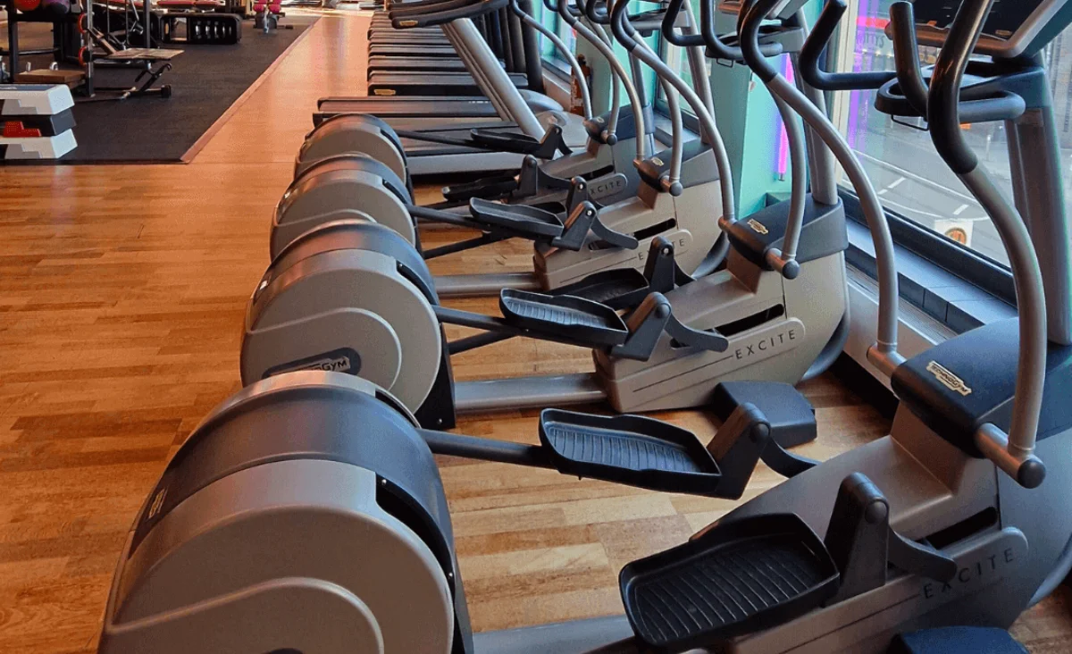 Innenansicht eines Fitnessstudios mit vielen Laufmaschinen und Fahrrädern