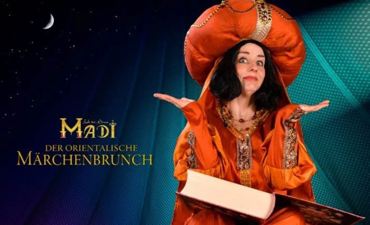 Eine Frau in einem orangefarbenen Kleid hält ein Buch in der Hand.