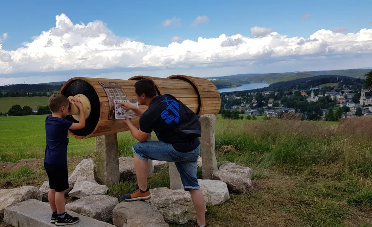 Ein Mann und ein Junge betrachten ein großes Holzfass in Wurzelrudis Erlebniswelt.