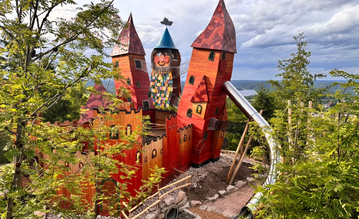 Spielplatz im Wurzelrudis Erlebniswelt mit einer Rutsche und einer Holzbrücke, die zum Spielen einlädt.