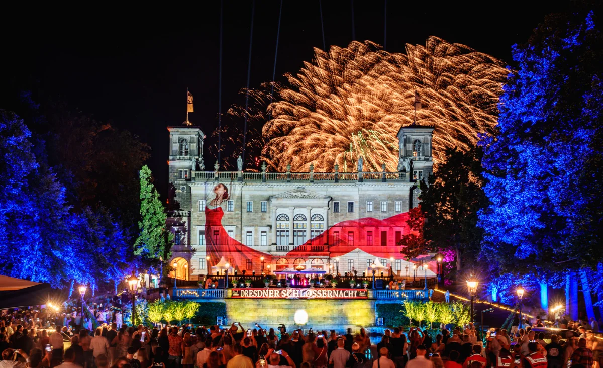 Ein großes Gebäude beleuchtet während der Dresdner Schlößernacht Lichtershow und Feuerwerk im Hintergrund