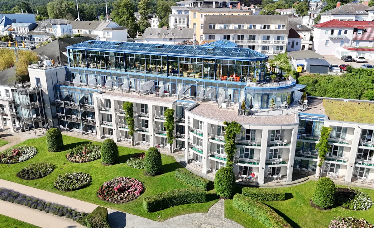 Das Gebäude des Hotel Kaiserhof Heringsdorf ist von einer gepflegten Gartenanlage mit geometrisch angelegten Wegen und Blumenbeeten umgeben.