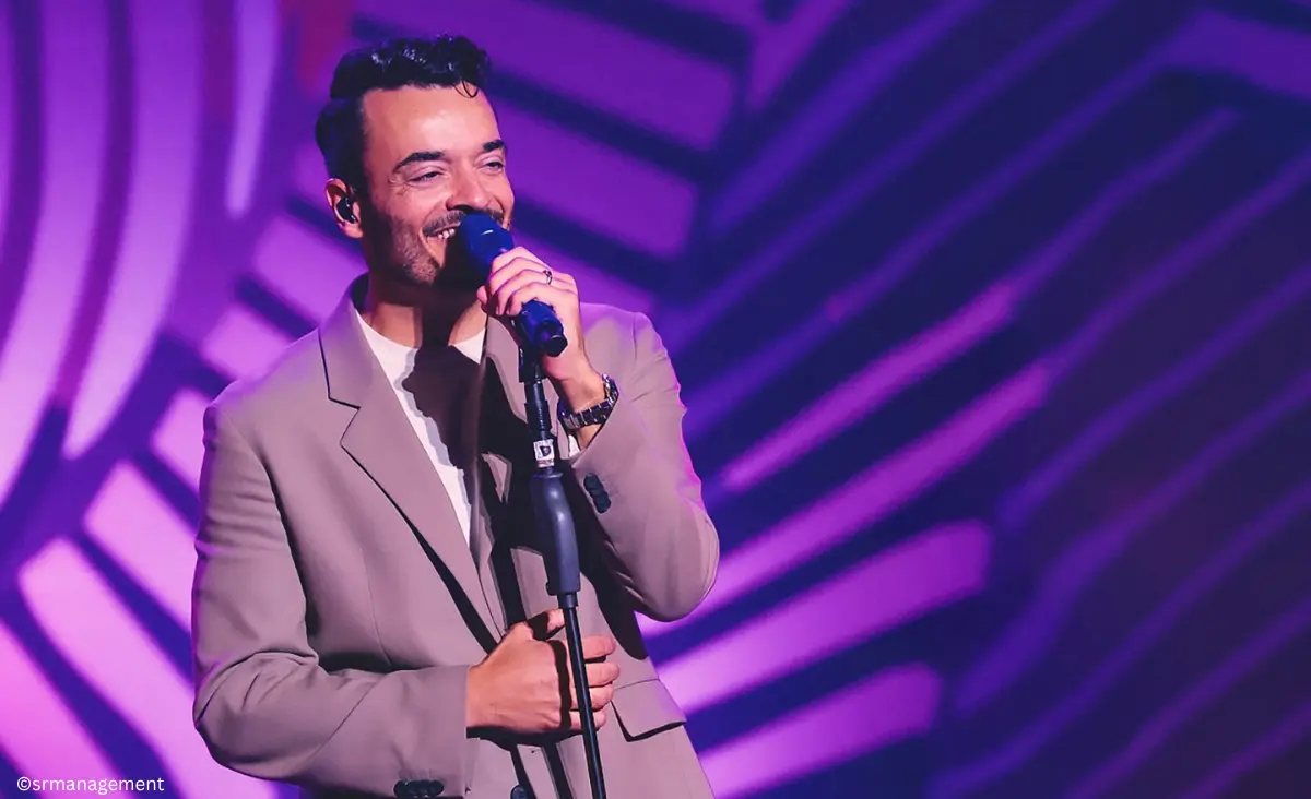 Giovanni Zarrella singt mit Mikrofon auf der Bühne vor violettem Hintergrund